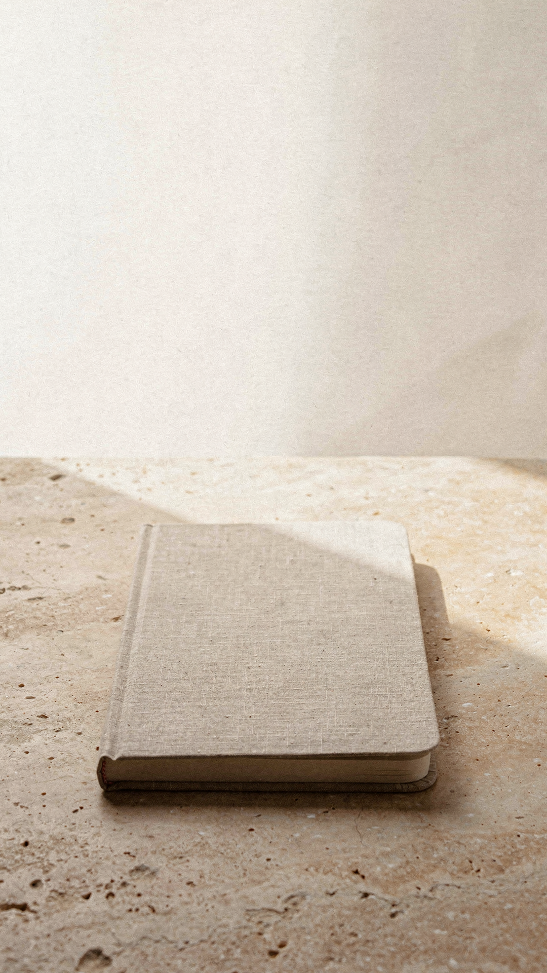 a linen notebook beside a ceramic cup on a warm desk